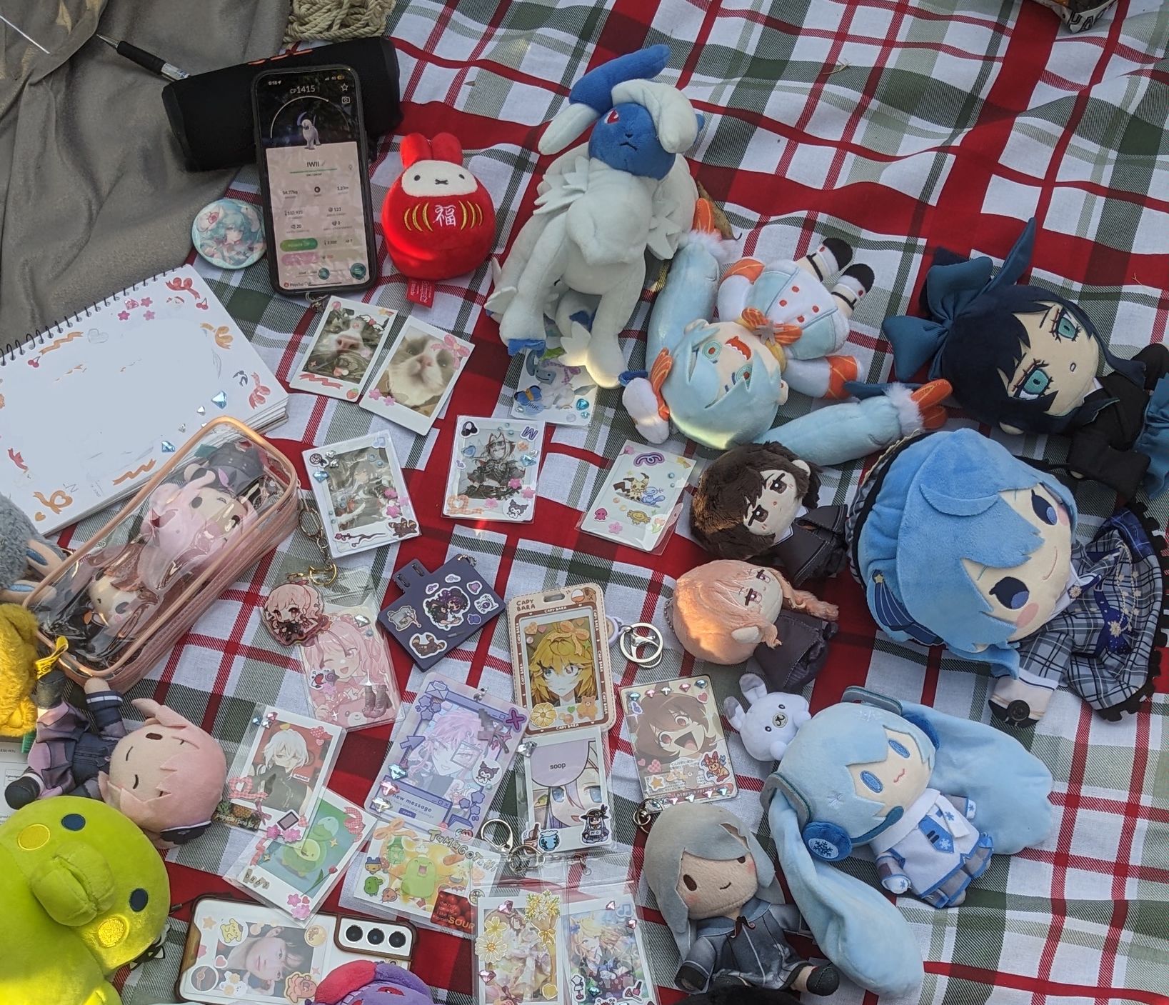 photo of a picnic blanket covered in various plushies and decorated photocard holders/toploaders